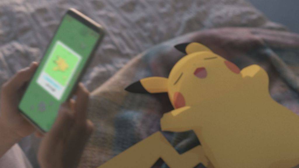 昏昏欲睡的皮卡丘的圖像,一個人使用Pokemon睡眠應用程序拿著電話